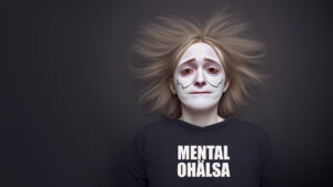 Kvinna med psykisk ohälsa stirrar på dig. På hennes tröja står texten "MENTAL OHÄLSA"